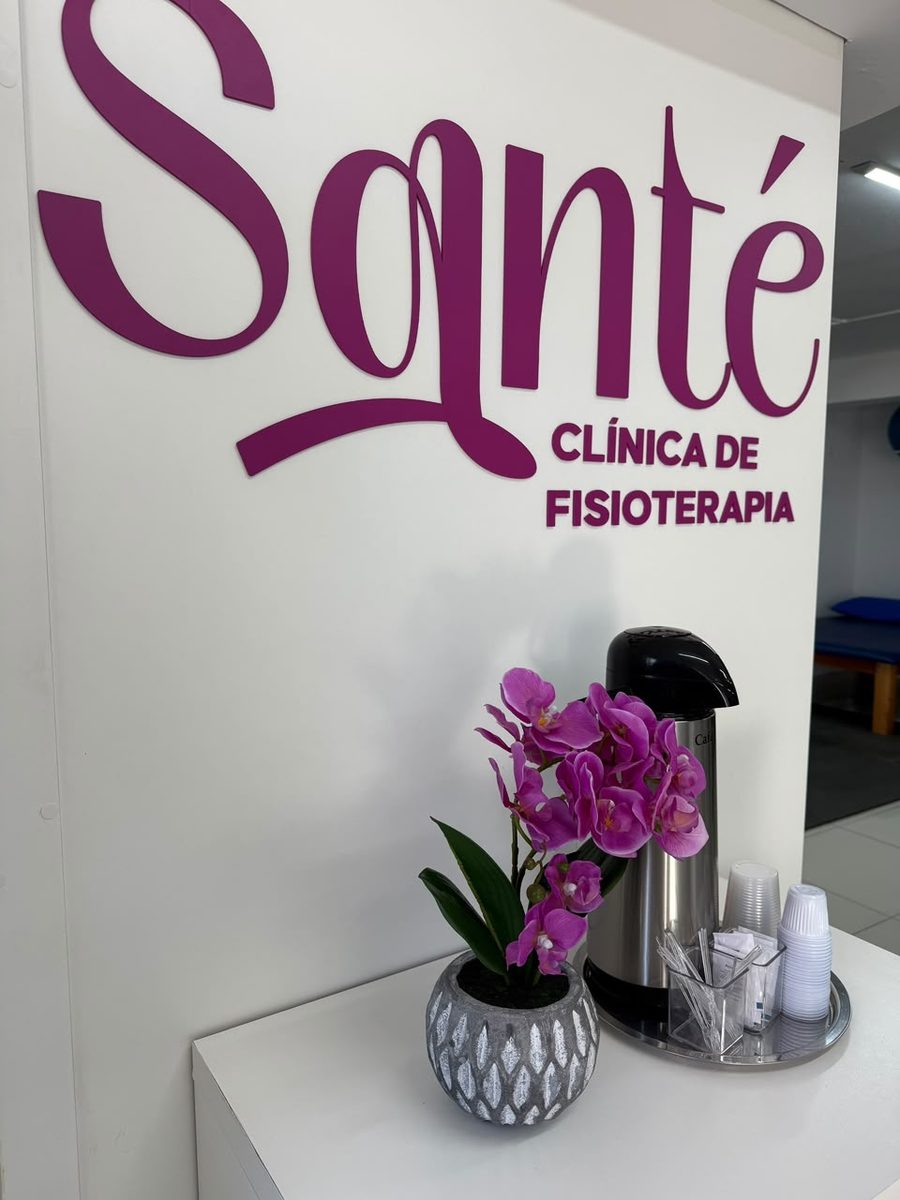 Marca Santé na parede da recepção, com uma orquídea