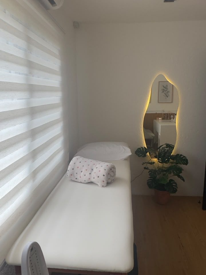 Sala de atendimento individual com maca, espelho iluminado e planta